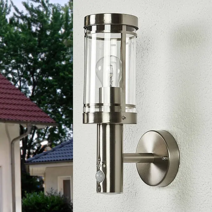 Lindby Außenwandleuchte Djori - alu / grau / zink, IP44 - Gebürstete Metall-Außenwandleuchte mit Klarglaszylinder, sichtbarer Glühbirne und Bewegungsmelder, an einer Hauswand montiert.