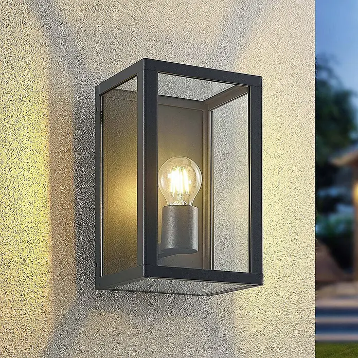 Lindby Außenwandleuchte Giavanna - 17,1 x 18 x 28 cm, schwarz, schwarz, IP44 - Dunkelgraue rechteckige Außenwandleuchte mit Klarglasscheiben und beleuchteter LED-Glühfadenlampe an einer strukturierten Wand.