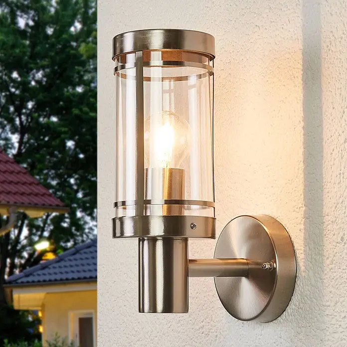 Lindby Außenwandleuchte Djori - alu / grau / zink, IP44 - Gebürstete Edelstahl-Außenwandleuchte mit Klarglaszylinder, an einer Außenwand montiert, spendet warmes Licht.