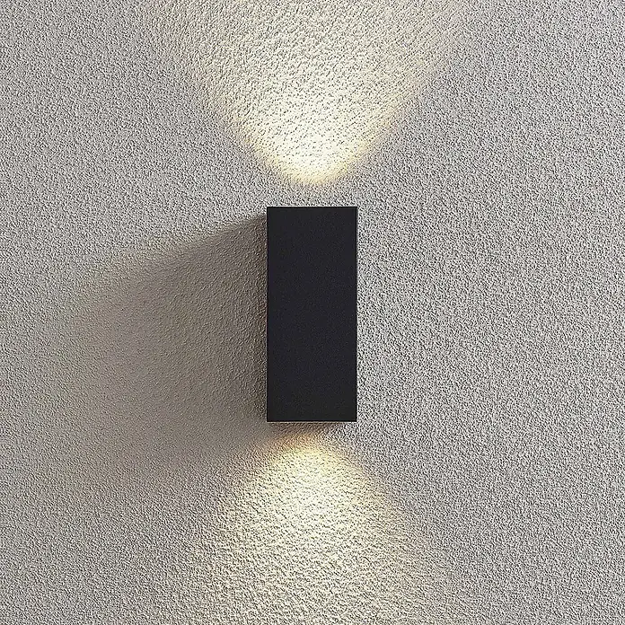 Lucande Außenwandleuchte Lavina - 7,8 x 7 x 16,5 cm, alu / grau / zink, alu / grau / zink, IP65 - Schwarze rechteckige Wandleuchte, die warmes Licht nach oben und unten auf eine strukturierte Wand strahlt.