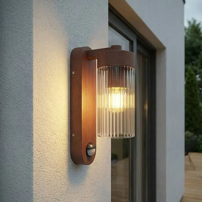 Lindby Außenwandleuchte Kaliro - braun / rost, klar / transparent, IP54 - Braune Außenwandleuchte mit geriffeltem Glas und Bewegungssensor, an einer Außenwand montiert.