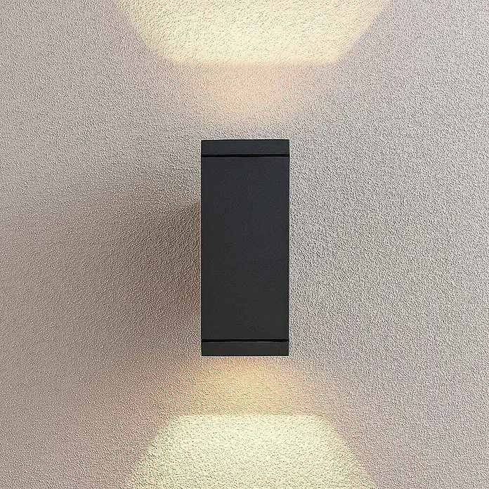 Lucande Außenwandleuchte Stani - alu / grau / zink, alu / grau / zink, IP54 - Schwarze rechteckige Außenwandleuchte, die warmes Licht nach oben und unten auf eine texturierte Wand wirft.