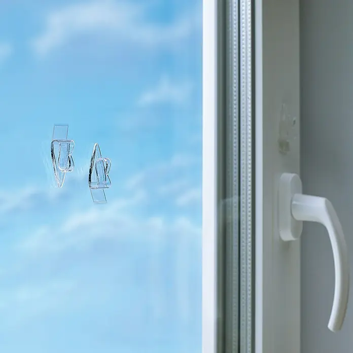 Tesa Klebehaken - Geeignet für: Glas, Belastbarkeit: 0,2 kg, 5 Stk., Transparent - Das Bild zeigt transparente Fensterhaken, die an einer Glasscheibe befestigt sind, ideal zur Befestigung von Dekorationen ohne Bohren.