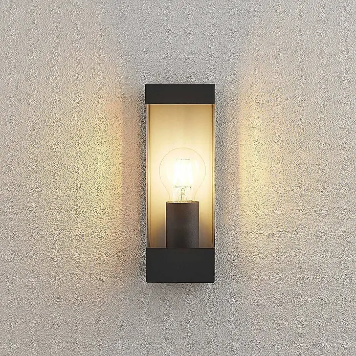 Lindby Außenwandleuchte Tilian - 8,5 x 9 x 25 cm, schwarz, schwarz, IP44 - Schwarze Wandleuchte aus Metall und Glas mit beleuchteter Birne, wirft warmes Licht auf eine strukturierte Wand.