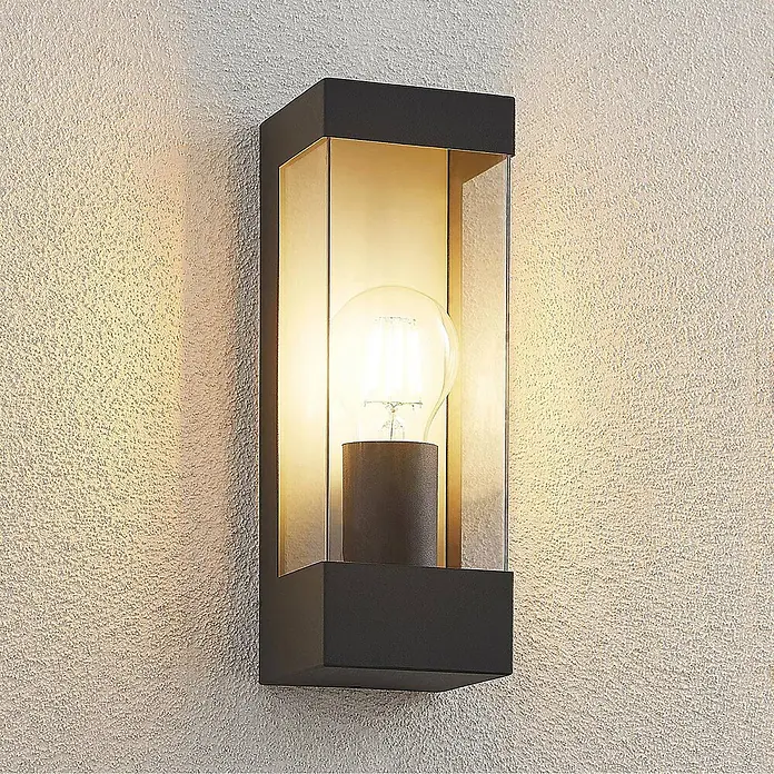Lindby Außenwandleuchte Tilian - 8,5 x 9 x 25 cm, schwarz, schwarz, IP44 - Schwarze, rechteckige Außenwandleuchte mit Klarglas und beleuchteter Glühbirne, an strukturierter Wand montiert.