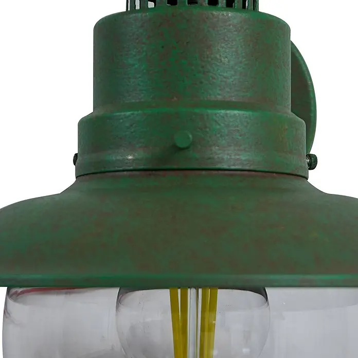 Lindby Außenwandleuchte Celinor - grün, grün, IP44 - Nahaufnahme einer verwitterten grünen Metall-Außenwandlaterne mit klarem Glasgehäuse und sichtbaren gelben LED-Filamenten.