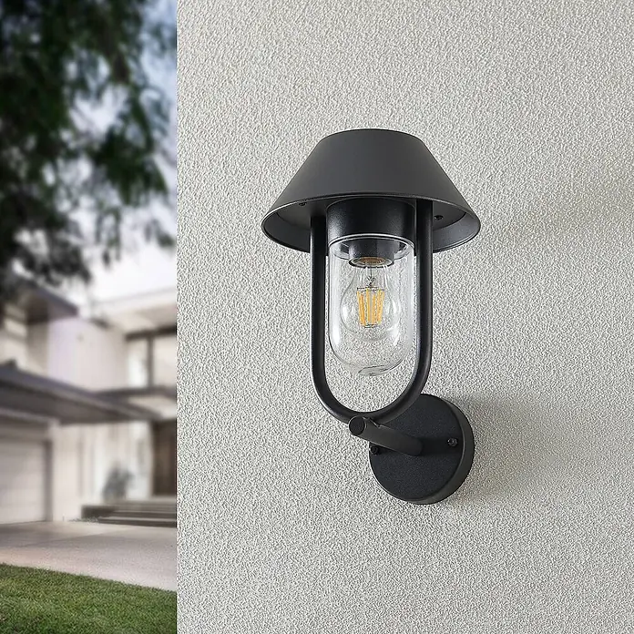 Lucande Außenwandleuchte Olinum - schwarz, schwarz, IP44 - Schwarze Außenwandleuchte mit Klarglas und LED-Birne an strukturierter Hausaußenwand.