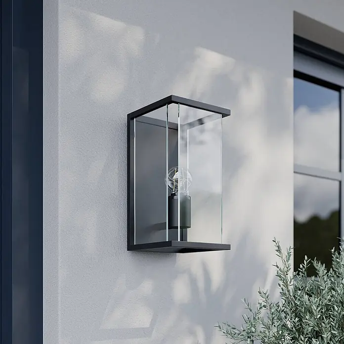 Lucande Außenwandleuchte Annalea - schwarz, klar / transparent, IP54 - Moderne schwarze Außenwandleuchte mit Klarglaspaneelen und sichtbarer Glühbirne, an Außenwand montiert.