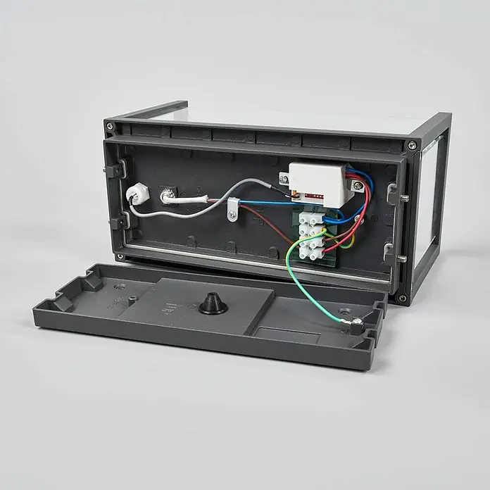 Lucande Außenwandleuchte Annalea - schwarz, klar / transparent, IP54 - Dunkelgraue Außenleuchte, geöffnet mit sichtbarer Innenverkabelung, Klemmenleiste und weißer Elektrikkomponente. Erdungskabel an der geöffneten Abdeckung befestigt.
