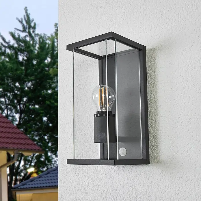Lucande Außenwandleuchte Annalea - schwarz, klar / transparent, IP54 - Schwarze Außenwandleuchte mit Glaspaneelen und sichtbarer LED-Glühbirne an strukturierter Wand. Mit Bewegungssensor.