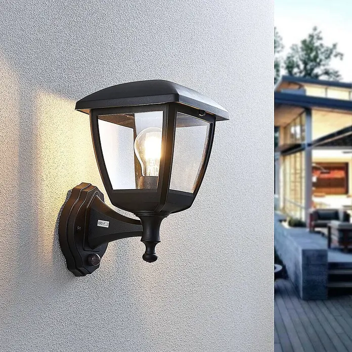 Lindby Außenwandleuchte Acelya - schwarz, schwarz, IP44 - Schwarze Außenwandleuchte mit klarem Glas, beleuchtet, und Bewegungssensor, an strukturierter Wand montiert.