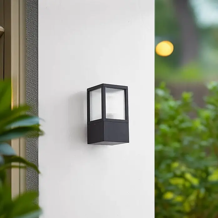 Lucande Außenwandleuchte Klemens - schwarz, schwarz, IP54 - Schwarze quadratische Außenwandleuchte mit geriffelten Glasscheiben, an einer Wand montiert.