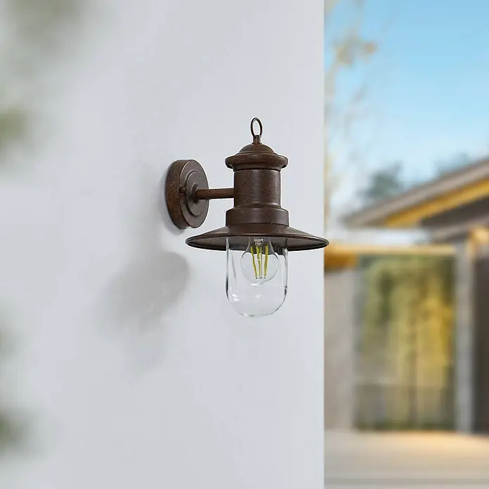 Lindby Außenwandleuchte Eloretta - braun / rost, braun / rost, IP44 - Rostbraune Außenwandleuchte mit Klarglas und LED-Birne, an einer Wand montiert.