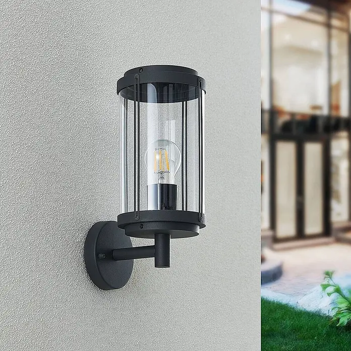 Lindby Außenwandleuchte Ojali - schwarz, IP44 - Zylindrische Außenwandleuchte aus schwarzem Metall und Klarglas mit sichtbarer Glühlampe.