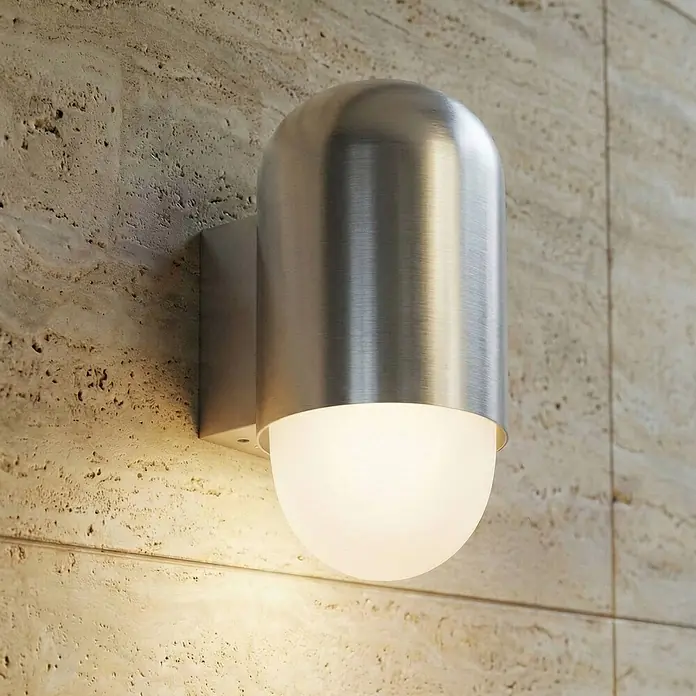 Lindby Außenwandleuchte Pilva - 13,3 x 10,5 x 21,5 cm, alu / grau / zink, weiß / opal, IP44 - Wandleuchte aus gebürstetem Edelstahl mit mattweißem Diffusor, an einer Steinwand montiert, spendet warmes Licht.