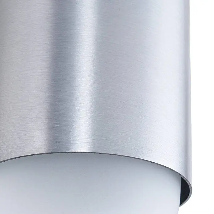 Lindby Außenwandleuchte Pilva - 13,3 x 10,5 x 21,5 cm, alu / grau / zink, weiß / opal, IP44 - Nahaufnahme einer gekrümmten, gebürsteten Silbermetalloberfläche, die einen weißen Diffusor teilweise bedeckt.
