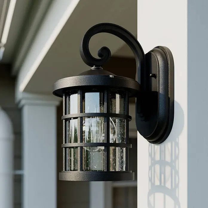 Lindby Außenwandleuchte Ankea - 19,4 x 15,2 x 28 cm, schwarz, IP23 - Schwarze Außenwandleuchte mit gesätem Glas und dekorativem Scrollarm, an weißem Pfeiler montiert.