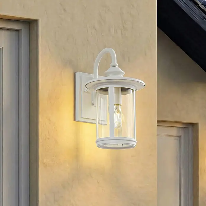 Lindby Außenwandleuchte Zayn - weiß / opal, weiß / opal, IP23 - Eine weiße Außenwandleuchte mit Klarglas und freiliegender Glühbirne, an einer strukturierten Wand montiert und warm leuchtend.