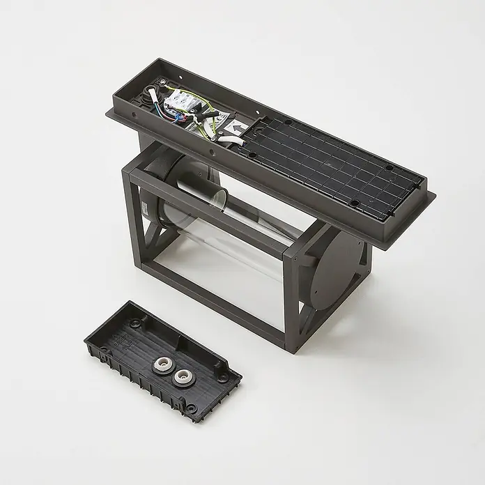 Lucande Außenwandleuchte Ferda - 22,6 x 16 x 38 cm, schwarz, schwarz, IP44 - Demontierte dunkelgraue Außenwandleuchte mit Solarpanel, zeigt interne Verkabelung, Klarglaszylinder und separate Montagebasis.