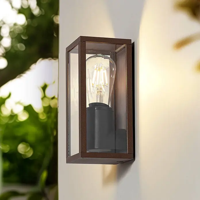 Lindby Außenwandleuchte Robigus - braun / rost, braun / rost, IP54 - Rechteckige Outdoor-Wandleuchte mit dunkelbraunem Rahmen, Klarglas und beleuchteter Edison-LED-Lampe an einer Wand.