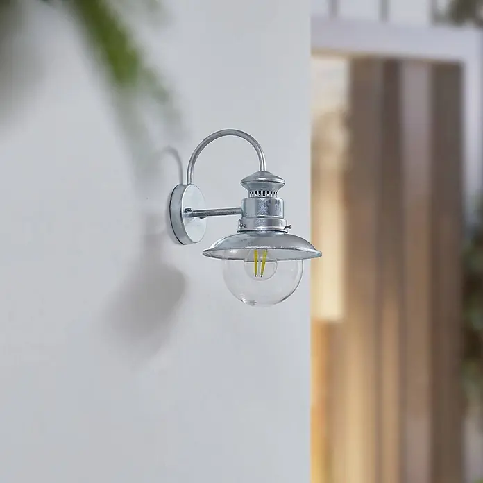 Lindby Außenwandleuchte Celinor - chrom / silber, chrom / silber, IP44 - Wandlampe aus verzinktem Metall mit gebogenem Arm, Glockenschirm und klarer Glaskugel mit LED-Glühfadenlampe.