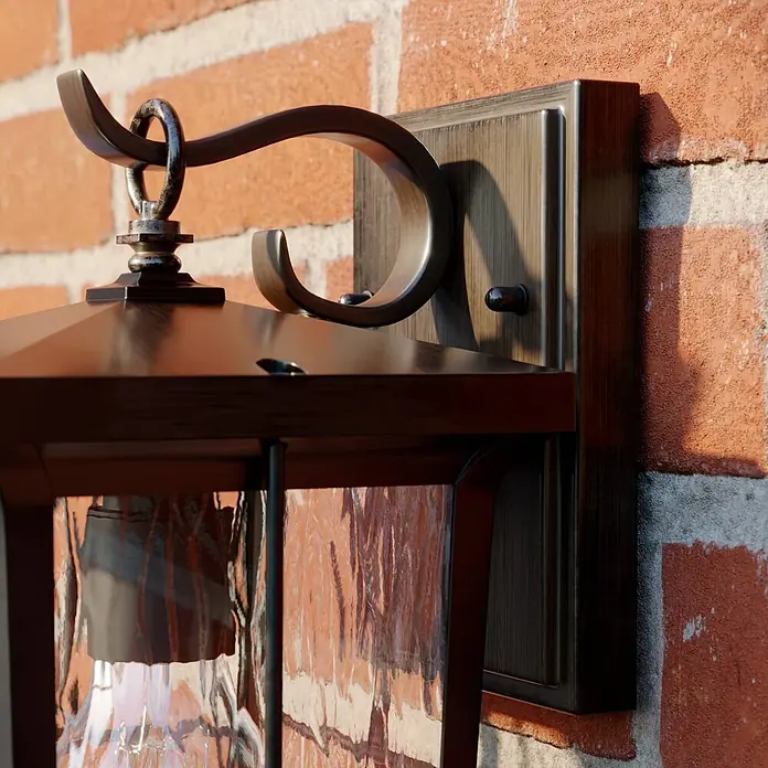 Lindby Außenwandleuchte Charmaine - 18,6 x 15,3 x 28,6 cm, braun / rost, braun / rost, IP23 - Außenwandleuchte aus gealterter Bronze mit Strukturglas, an einer Ziegelwand montiert.