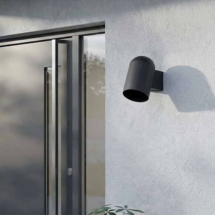 Lindby Wandleuchte aussen in schwarz, Aussenlampe Wand -  - Schwarze Außenwandleuchte an einer strukturierten Wand neben einer Glastür.