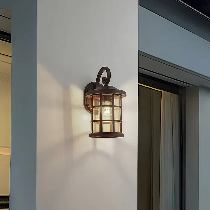Lindby Wandleuchte aussen in rost, amber getönt, Aussenlampe Wand -  - Rustikale Außenwandleuchte aus dunkler Bronze mit bernsteinfarbenem Glasgitter an einer Außenwand.