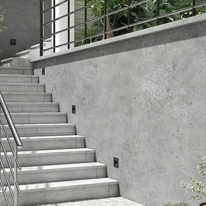 Arcchio Außenwandleuchte Zamo - schwarz, IP65 - Schwarze rechteckige Leuchten in einer Betonwand entlang einer Treppe, die Stufen beleuchten.