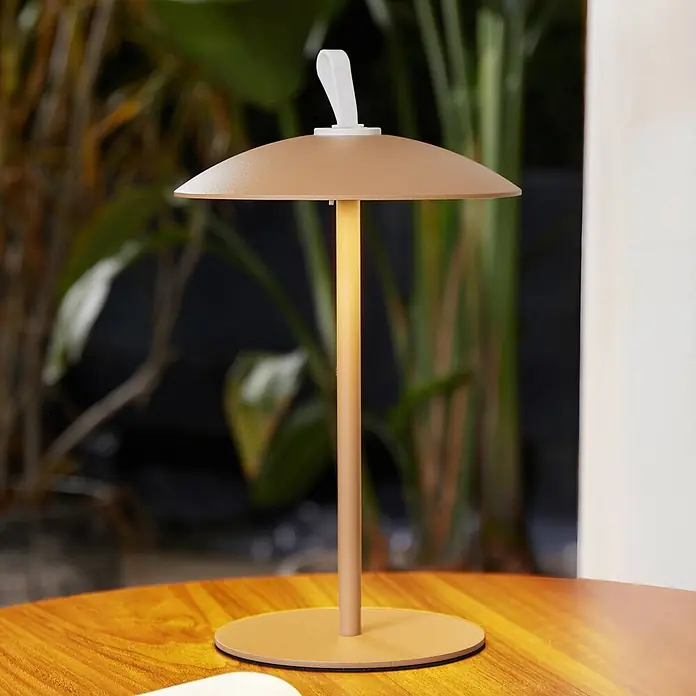 Lindby LED-Tischleuchte Kanani - braun / rost, braun / rost, Warmweiß - Beleuchtete goldene tragbare Tischlampe mit Pilzschirm und weißem Griff auf Holztisch.
