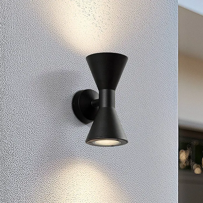 Lucande Außenwandleuchte Xalor - schwarz, IP65 - Schwarze Sanduhr-Wandleuchte mit Ober- und Unterlicht auf einer strukturierten Wand.