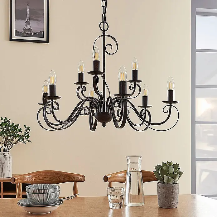 Lindby Kronleuchter Caleb - braun / rost, rostbraun, E14 - Dunkelbronze-rustikaler 8-flammiger Kronleuchter mit LED-Kerzenlampen, der einen Esstisch beleuchtet.