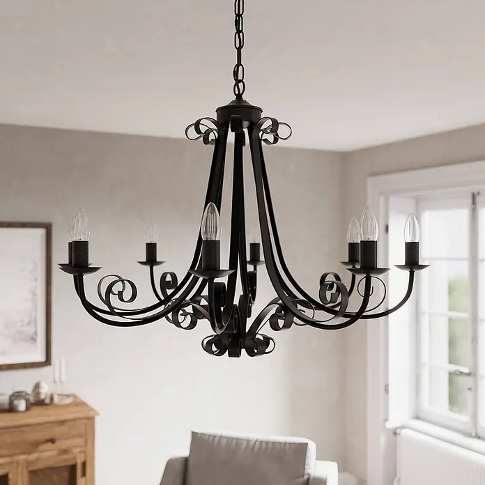 Lindby Kronleuchter Scaleria - antikbraun, E14 - Schwarzer Metall-Kronleuchter mit sechs kerzenförmigen Glühbirnen, hängt von der Decke in einem Raum mit natürlichem Licht.