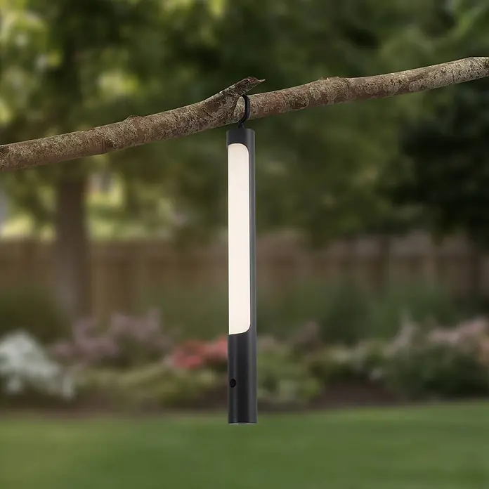 Lindby LED-Tischleuchte Kompis - alu / grau / zink, Warmweiß - Dunkle rechteckige Handleuchte mit leuchtendem weißem Panel, an einem Ast im Garten hängend.