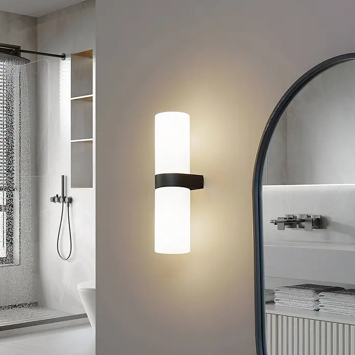 Lucande Wandleuchte Basolo - weiß / opal, E14 - Schwarze und weiße zylindrische Wandleuchte mit Auf- und Ablicht in einem modernen Badezimmer.