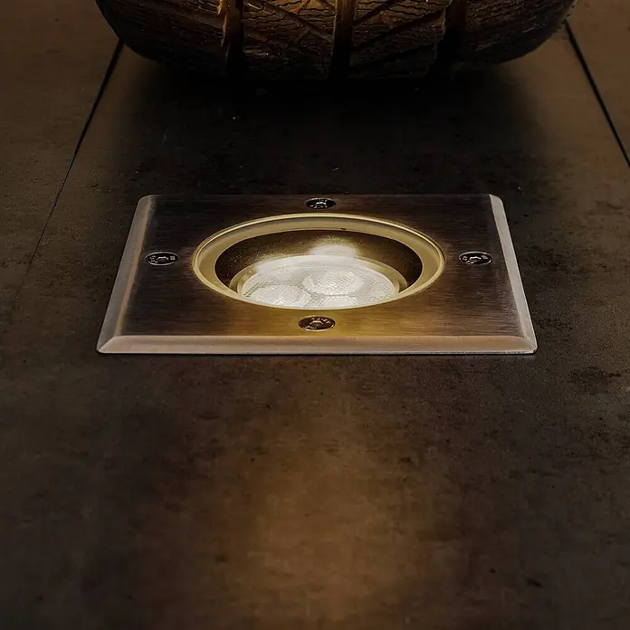 Lucande LED-Gartenstrahler JOS - 3.000 K - Quadratische, bronzefarbene Bodeneinbauleuchte mit warmem Licht, bündig in dunklem Boden installiert.
