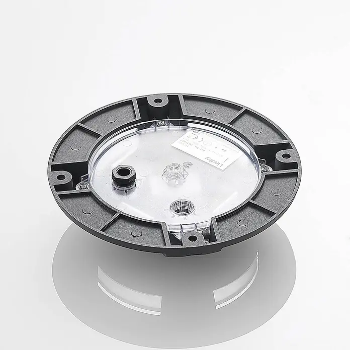 Lindby LED-Gartenstrahler Cormac - 3.000 K - Runde dunkelgraue Leuchtenbasis mit transparenter Abdeckung und sichtbaren internen Komponenten.