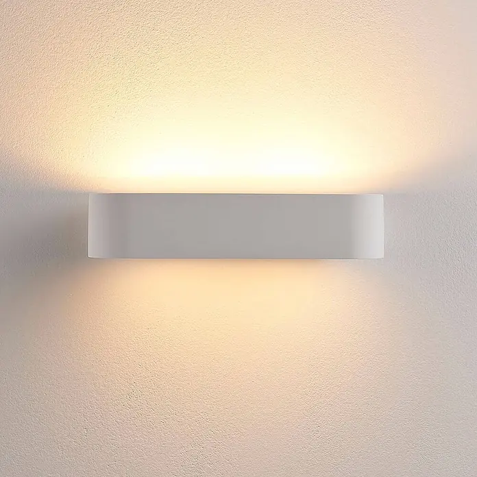 Lindby Wandleuchte Fioni - L x B x H: 10,5 x 30 x 6,5 cm, weiß / opal, G9 - Weiße, rechteckige Wandleuchte mit abgerundeten Kanten, die warmes gelbes Licht nach oben und unten auf eine texturierte Wand wirft.