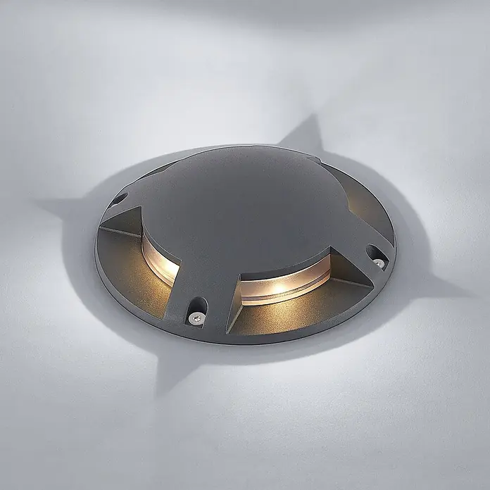 Lindby LED-Gartenstrahler Cormac - 3.000 K - Rundes, dunkelgraues Bodeneinbauleuchte mit vier seitlichen Lichtöffnungen und warmweißer Beleuchtung.