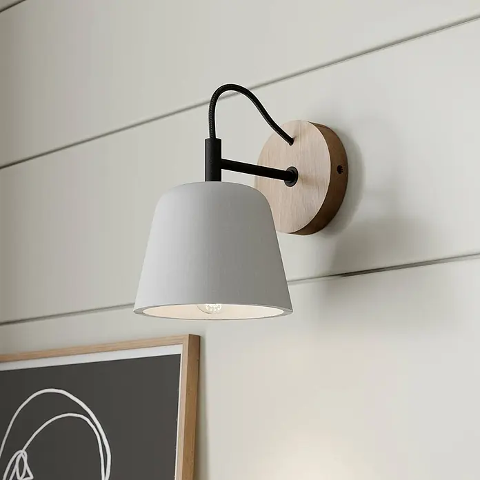 Lucande Wandleuchte Kalinda - L x B x H: 20 x 15 x 20 cm, Holz hell, alu / grau / zink, E14 - Wandleuchte mit hellgrauem Schirm, schwarzem Arm und runder Holzbasis, an einer Wand montiert.