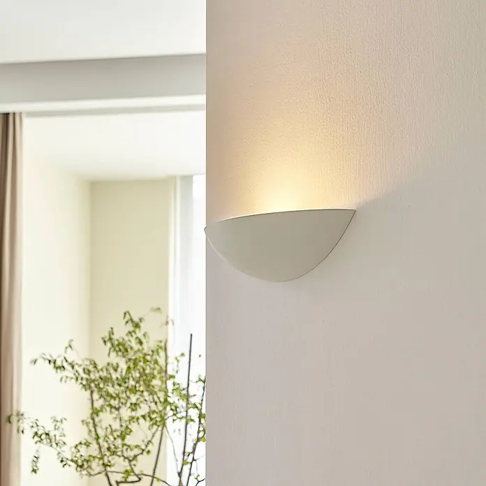 Lindby Wandleuchte Guilia - weiß / opal, weiß / opal, E27 - Halbrunde weiße Wandleuchte, die warmes Licht nach oben auf eine strukturierte Wand wirft.