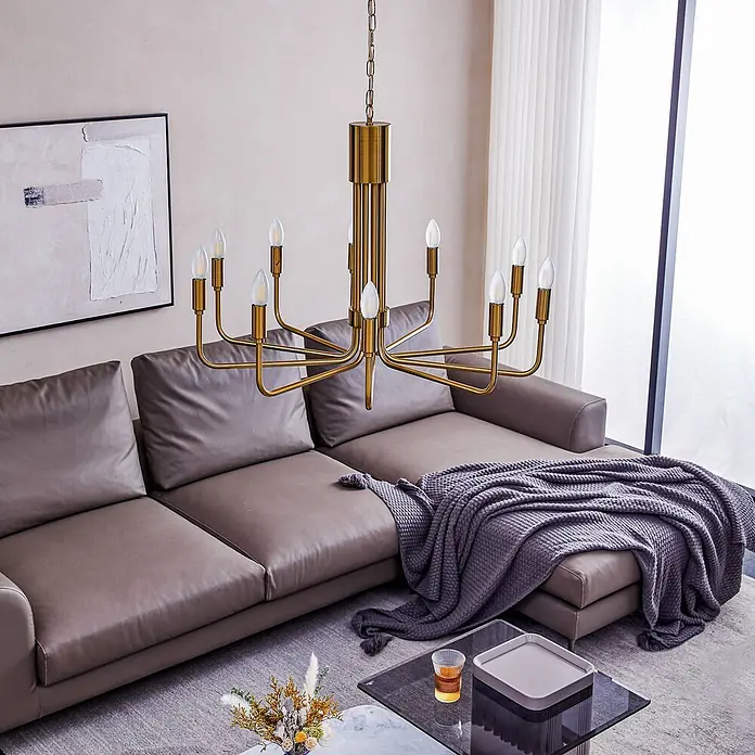 Lindby Kronleuchter Elanova - messing, E14 - Goldener Kronleuchter mit mehreren Armen und sichtbaren Glühbirnen, hängt in einem modernen Wohnzimmer über einem Ecksofa.