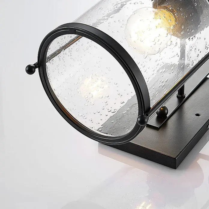 Lindby Wandleuchte Rozalie - L x B x H: 22 x 18 x 44 cm, schwarz, E27 - Wandleuchte aus schwarzem Metall mit zylindrischem, blasigem Glasschirm und sichtbarer Glühbirne auf schwarzem Sockel.