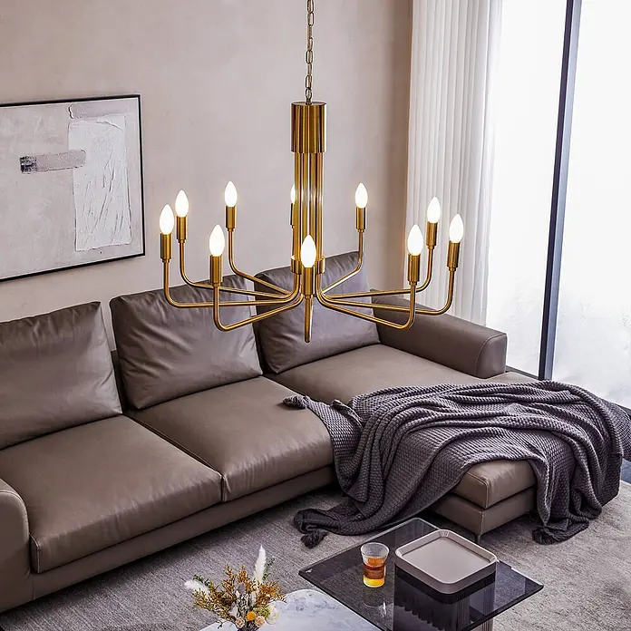Lindby Kronleuchter Elanova - messing, E14 - Goldener, moderner Kronleuchter mit zehn Kerzenlampen hängt über einem Ecksofa im Wohnzimmer.