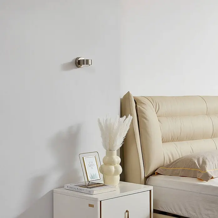 Lindby Wandleuchte Jyla - L x B x H: 10,5 x 8 x 7 cm, alu / grau / zink, 2GX53 - Gebürstete Metall-Wandleseleuchte neben einem Bett.