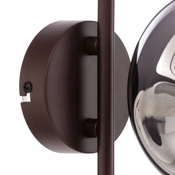 Lindby Wandleuchte Valentina - braun / rost, alu / grau / zink, E14 - Nahaufnahme einer matten braunen runden Wandhalterung mit vertikaler Stange, Teil einer Leuchte mit reflektierender Kugel.