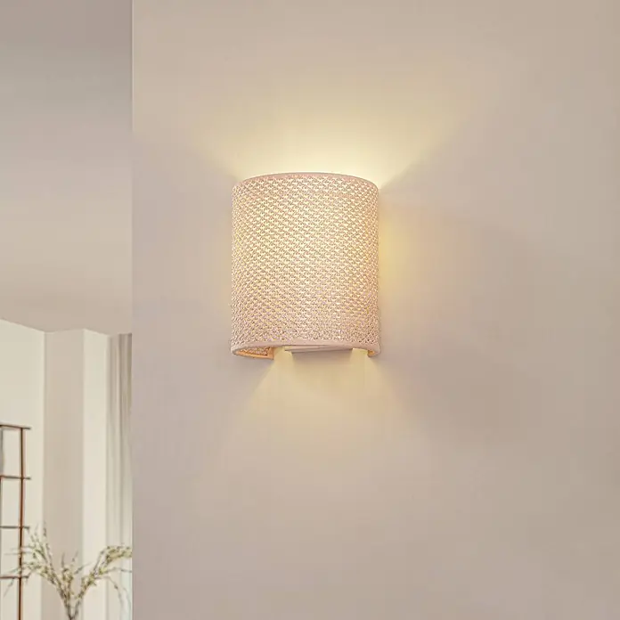 Lindby Wandleuchte Soula - L x B x H: 18 x 15 x 20 cm, creme / amber, E27 - Helle geflochtene Wandleuchte, die warmes Licht nach oben und unten auf eine helle Wand wirft.