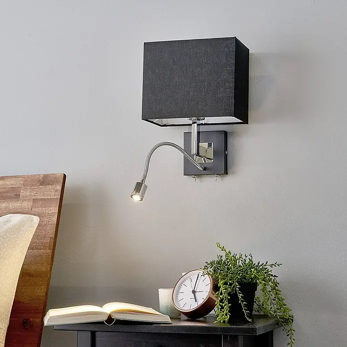 Lucande Wandleuchte Rebekka - L x B x H: 15 x 23,5 x 31,5 cm, chrom / silber, schwarz, E27 - Wandleuchte mit rechteckigem schwarzem Stoffschirm und integrierter flexibler Chrom-LED-Leselampe, über einem Nachttisch montiert.
