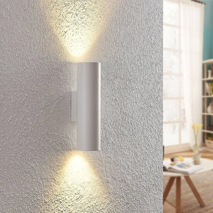 Arcchio Wandleuchte Brinja - L x B x H: 7,2 x 6 x 22,5 cm, weiß / opal, weiß / opal, GU10 - Weiße zylindrische Wandleuchte, die eine strukturierte Wand nach oben und unten beleuchtet, in einem Wohnzimmer.