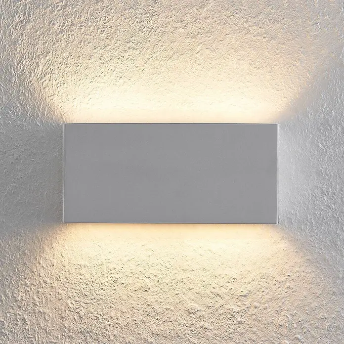Lindby Wandleuchte Mavora - L x B x H: 7 x 25 x 12 cm, weiß / opal, G9 - Rechteckige graue Wandleuchte, die warmes Licht nach oben und unten auf eine strukturierte Wand strahlt.